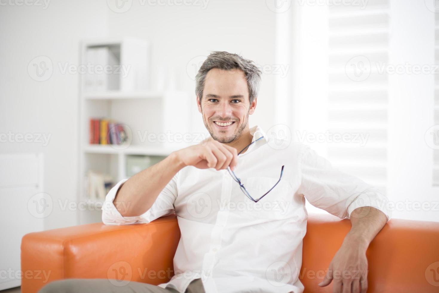 hombre atractivo sonriendo en un sofá foto