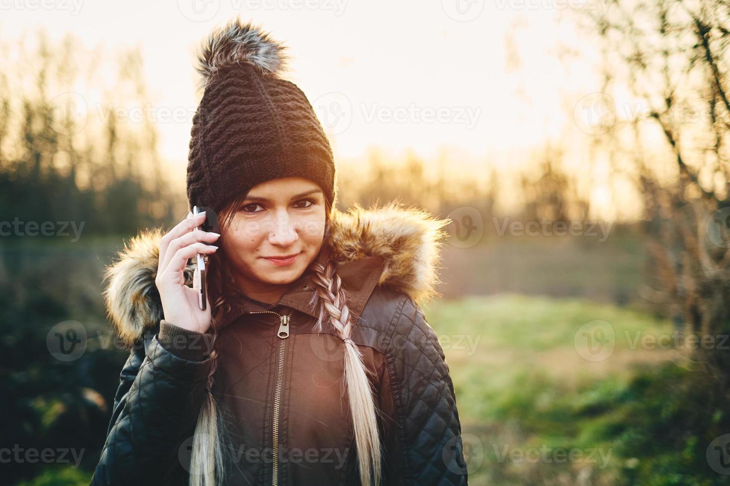 Young woman calling with mobile phone outdoors in winter photo