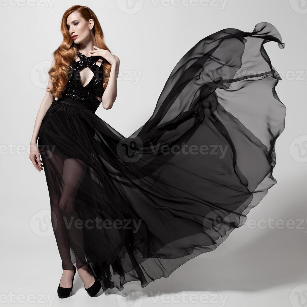 mujer de moda en vestido negro revoloteando. Fondo blanco. foto