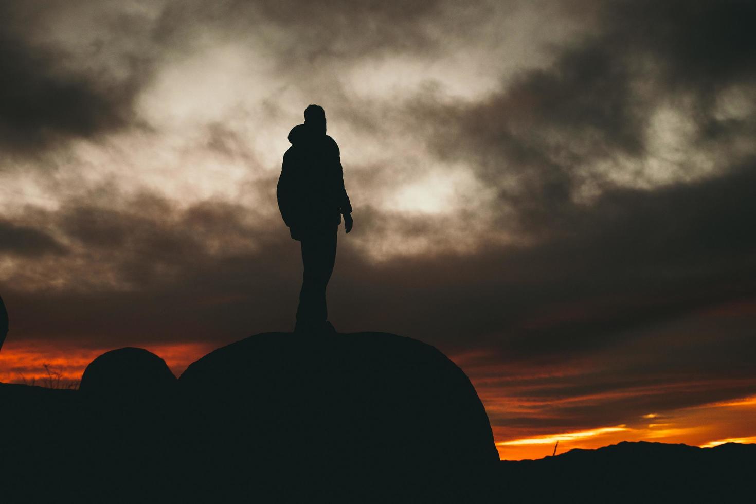 Man standing on rock during golden hour photo