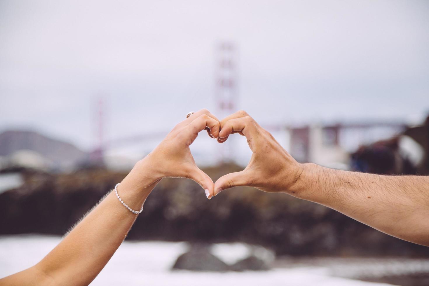 pareja formando corazón con las manos delante del puente golden gate foto