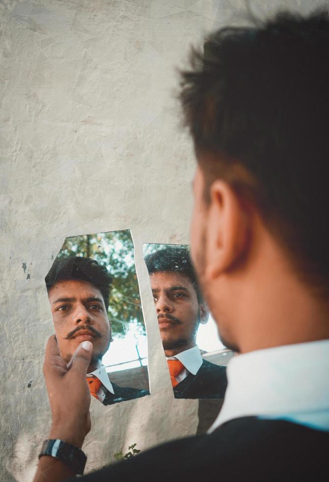 Man looking in broken mirror photo