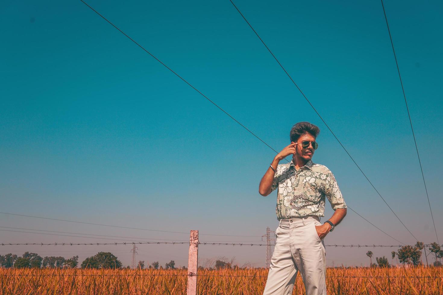 hombre con gafas de sol junto a la valla y el campo foto