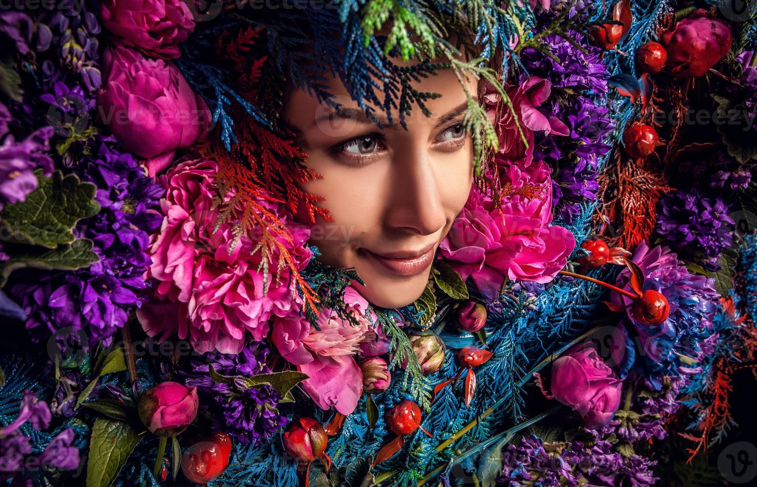 Retrato de niña de cuento de hadas rodeado de flores y plantas naturales. foto