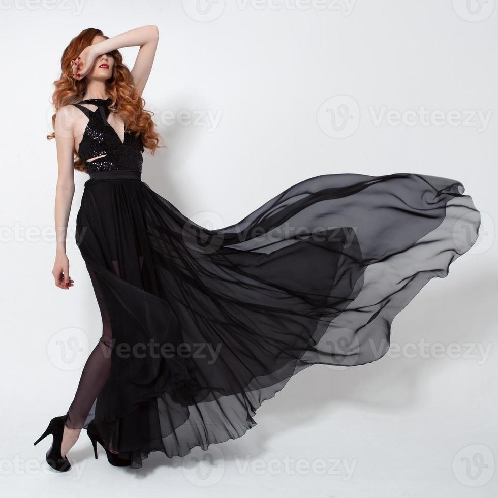 mujer de moda en vestido negro revoloteando. Fondo blanco. foto