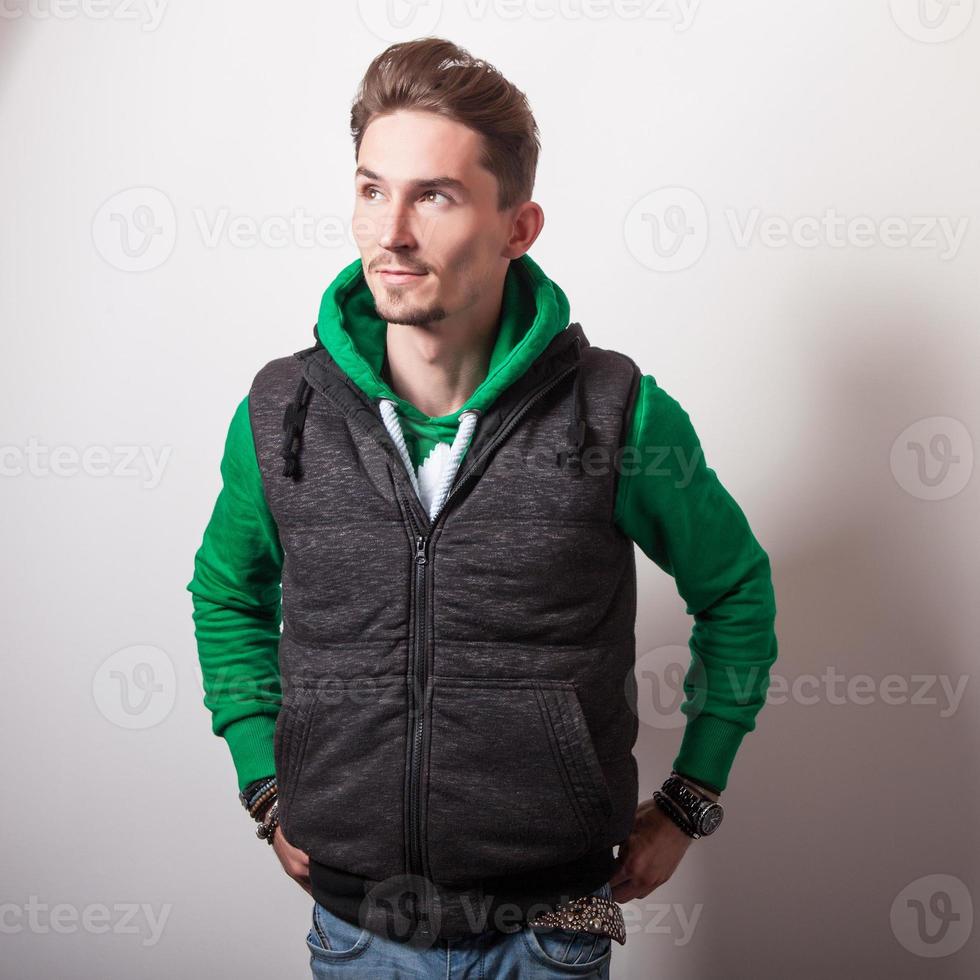 atractivo joven en chaleco gris y suéter verde. foto