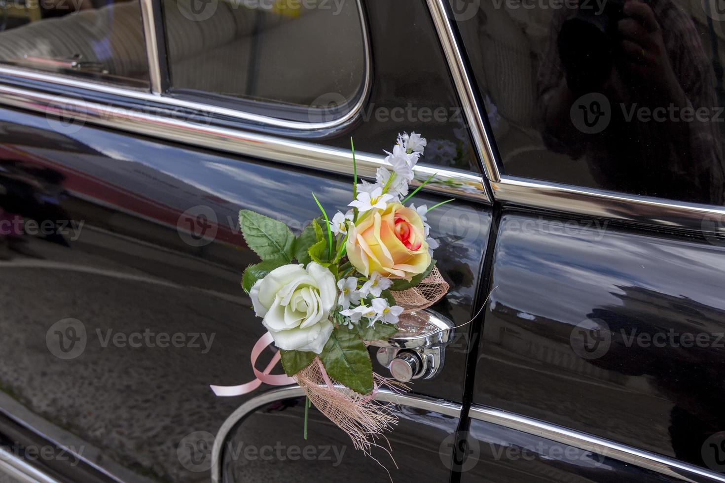 flores decorando un viejo coche de lujo negro foto