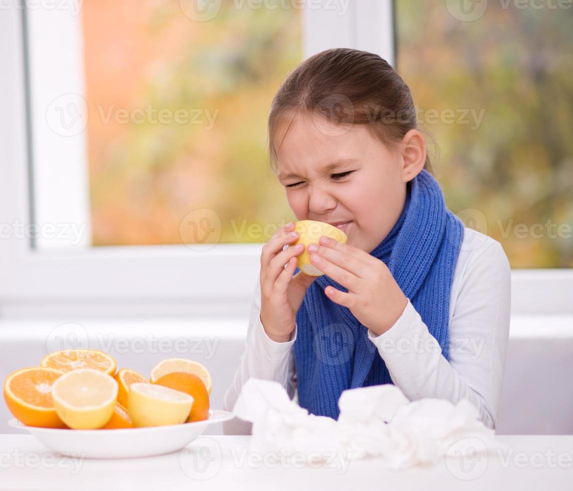 Girl tries to taste a slice of orange photo