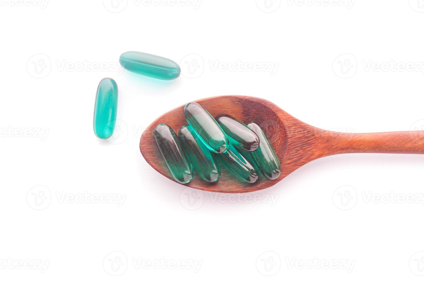 Cápsula de píldoras en cuchara de madera aislada foto