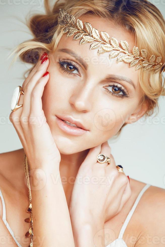 young blond woman dressed like ancient greek godess, gold jewelry photo