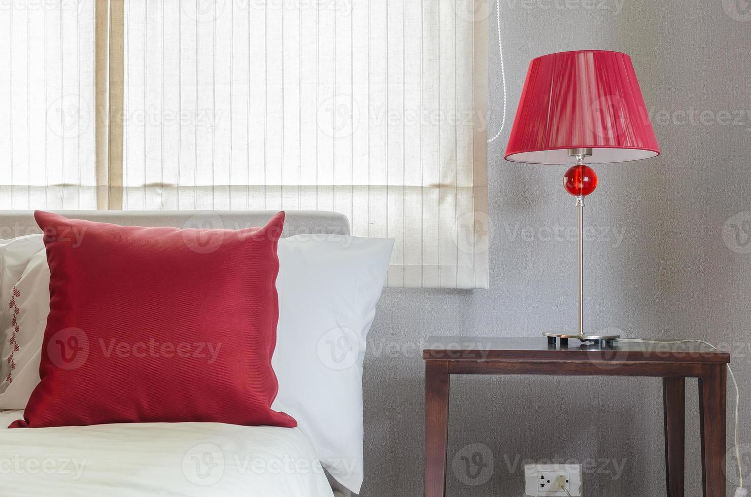 dormitorio con almohada roja y lámpara. foto