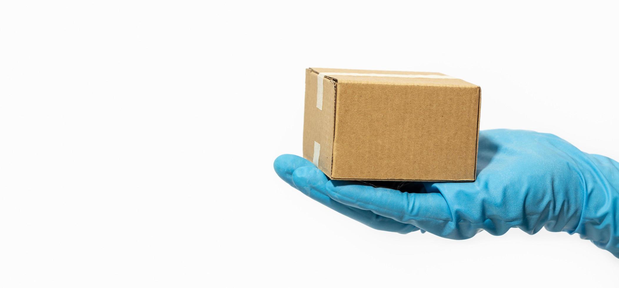 Delivery man holding cardboard box in rubber gloves photo