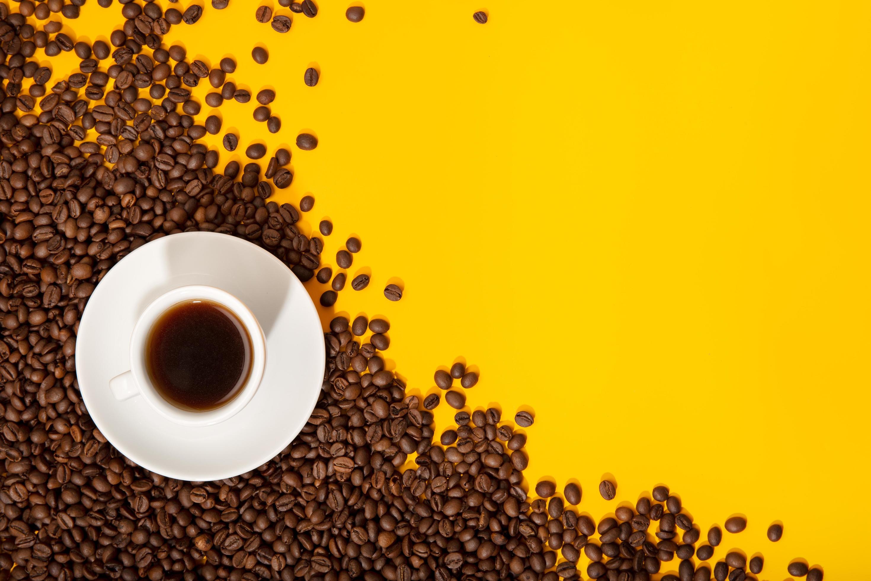Taza de café y granos tostados sobre fondo amarillo 1264045 Foto de