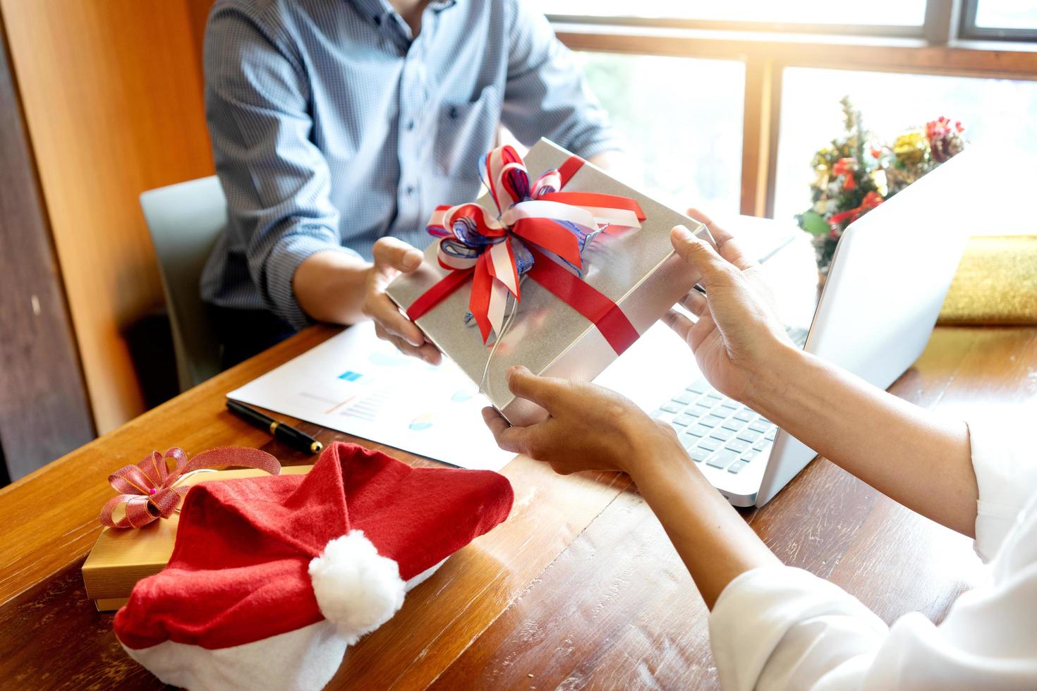 Coworkers exchanging Christmas presents in office photo