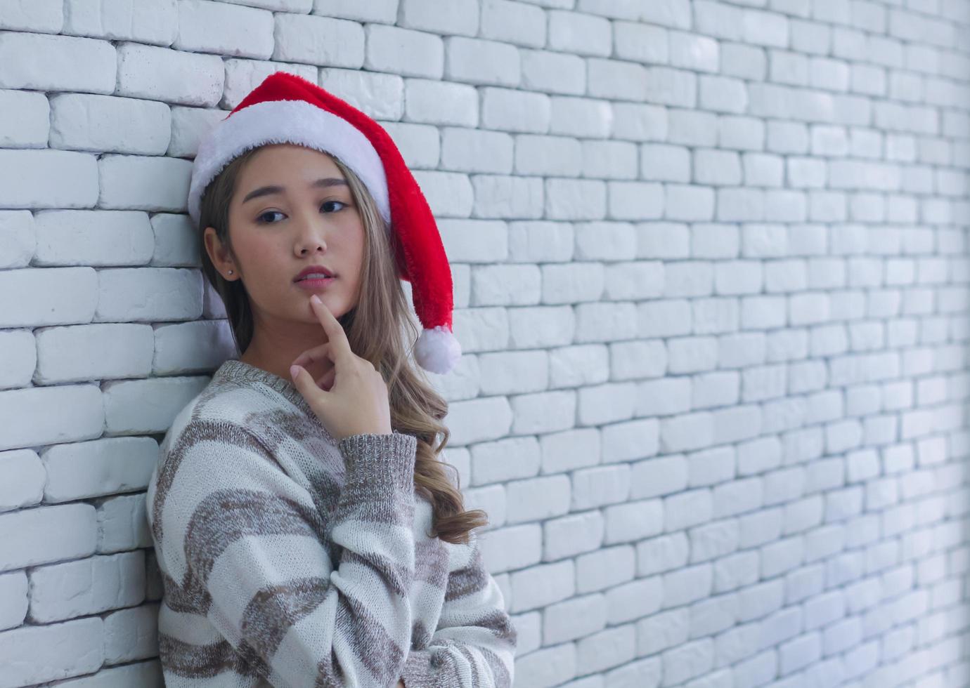 Mujer vistiendo un gorro de Papá Noel apoyado en la pared foto