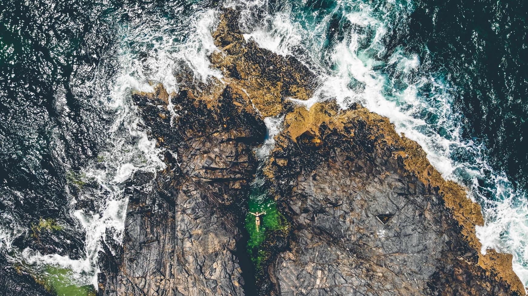 A woman floating in a small rocky pond photo