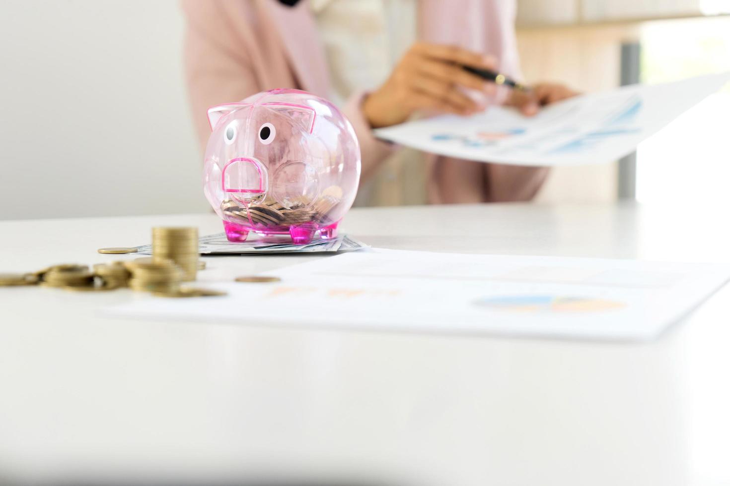 Businesswoman reviewing documents with piggy bank photo