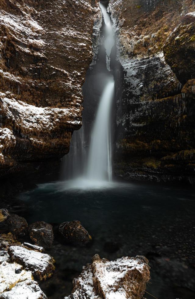 Waterfall on rocky mountain with snow photo