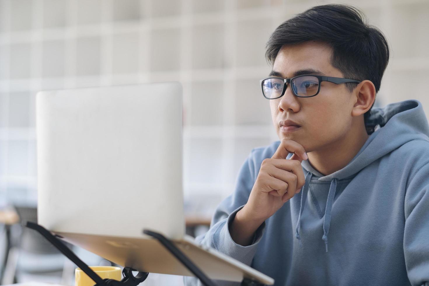 joven estudiante de collage usando la computadora para estudiar en línea foto