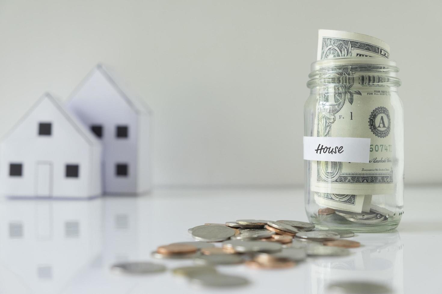 Savings jar with coins and wooden houses photo