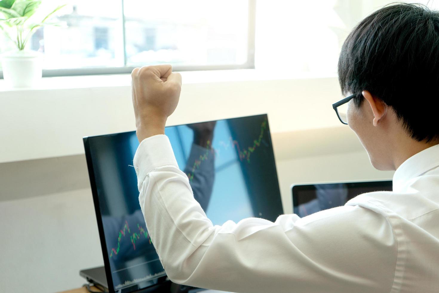 Young businessman at the computer watching the stock market photo