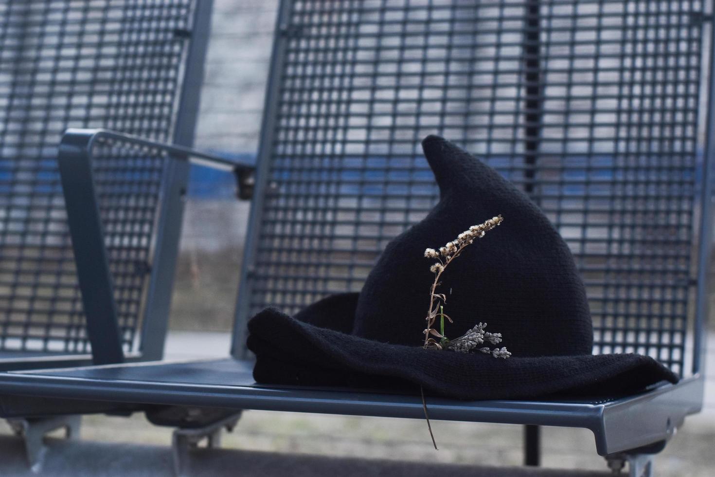 Witch hat with dried flowers left on bus stop photo