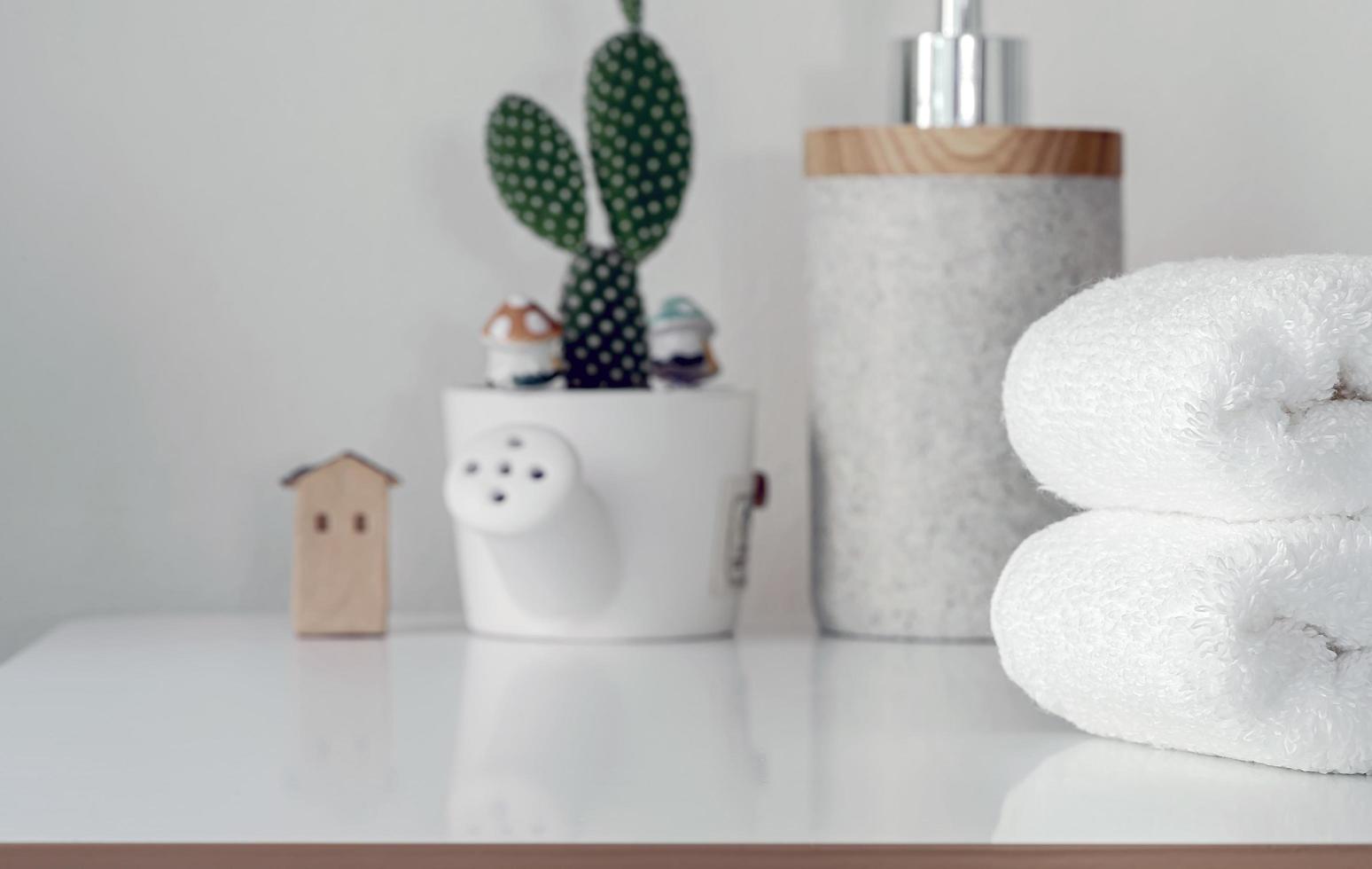 Stack of folded towels and a plant on a white table photo