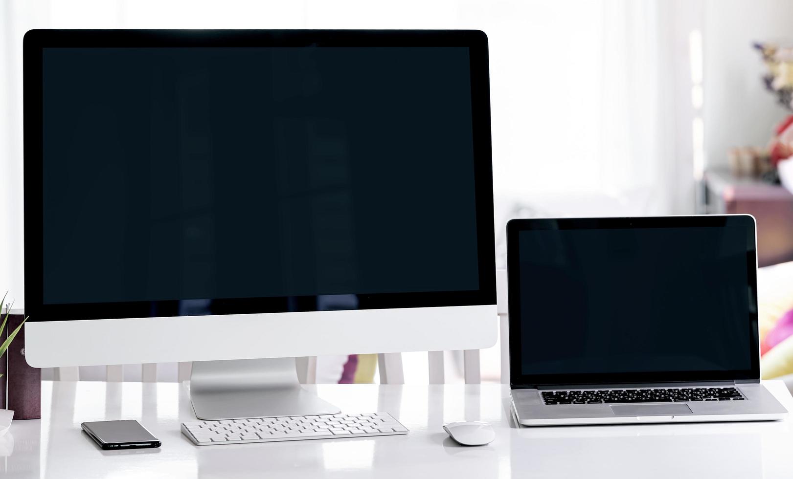 Computer and laptop mockup on a desk in an office photo