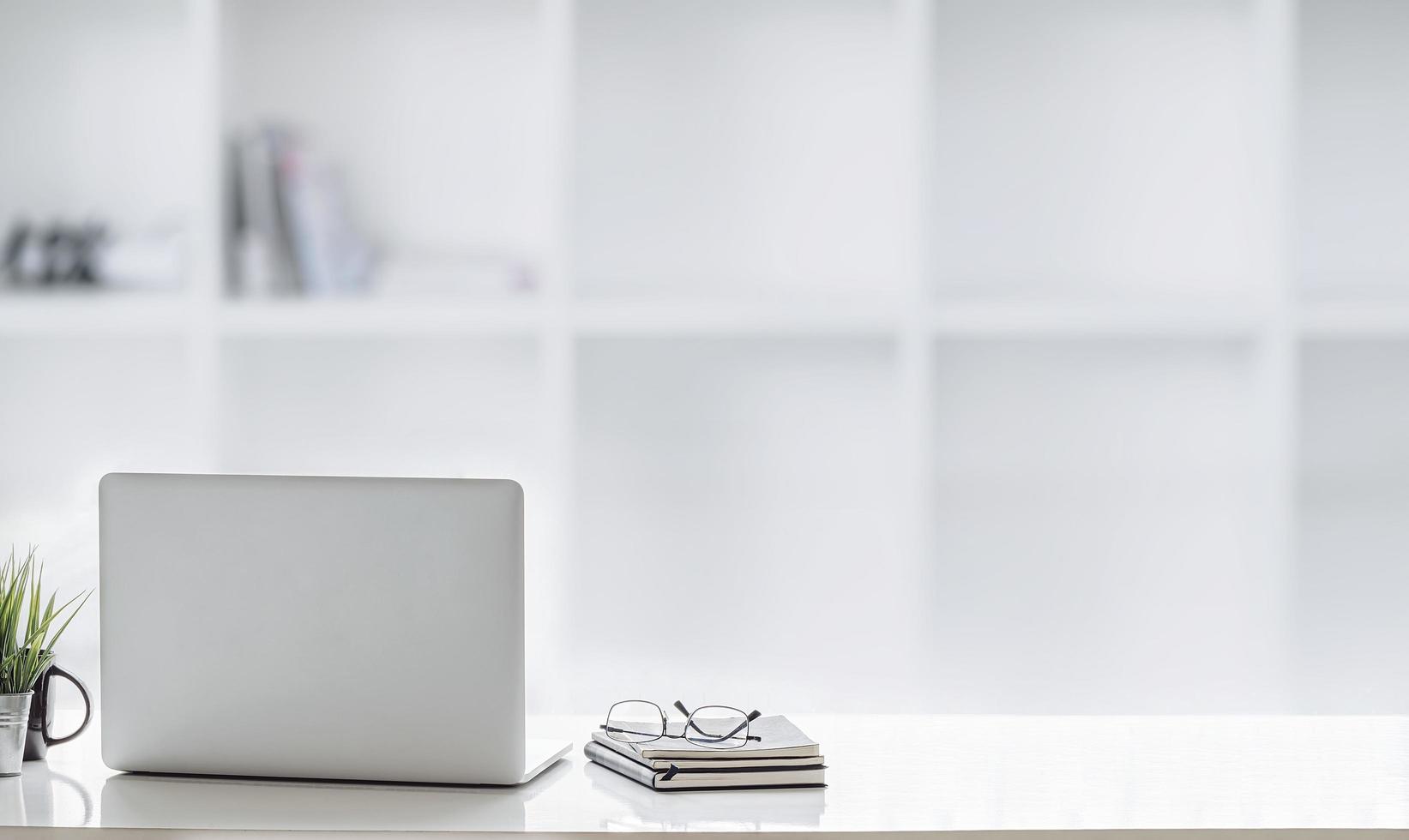 Laptop with glasses and notebooks on a desk photo