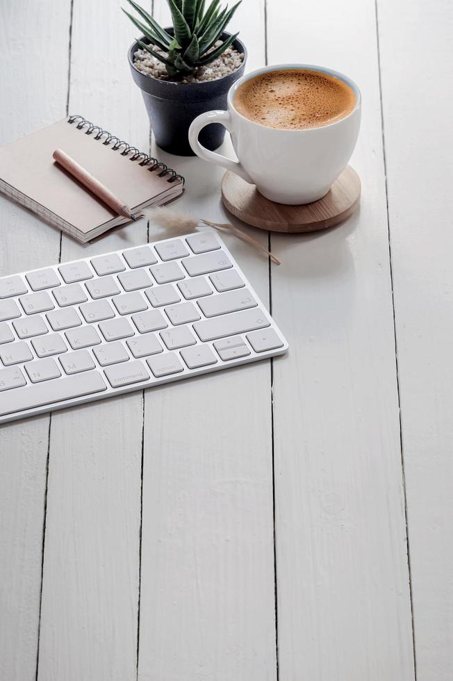 teclado, planta y café en una mesa de madera foto