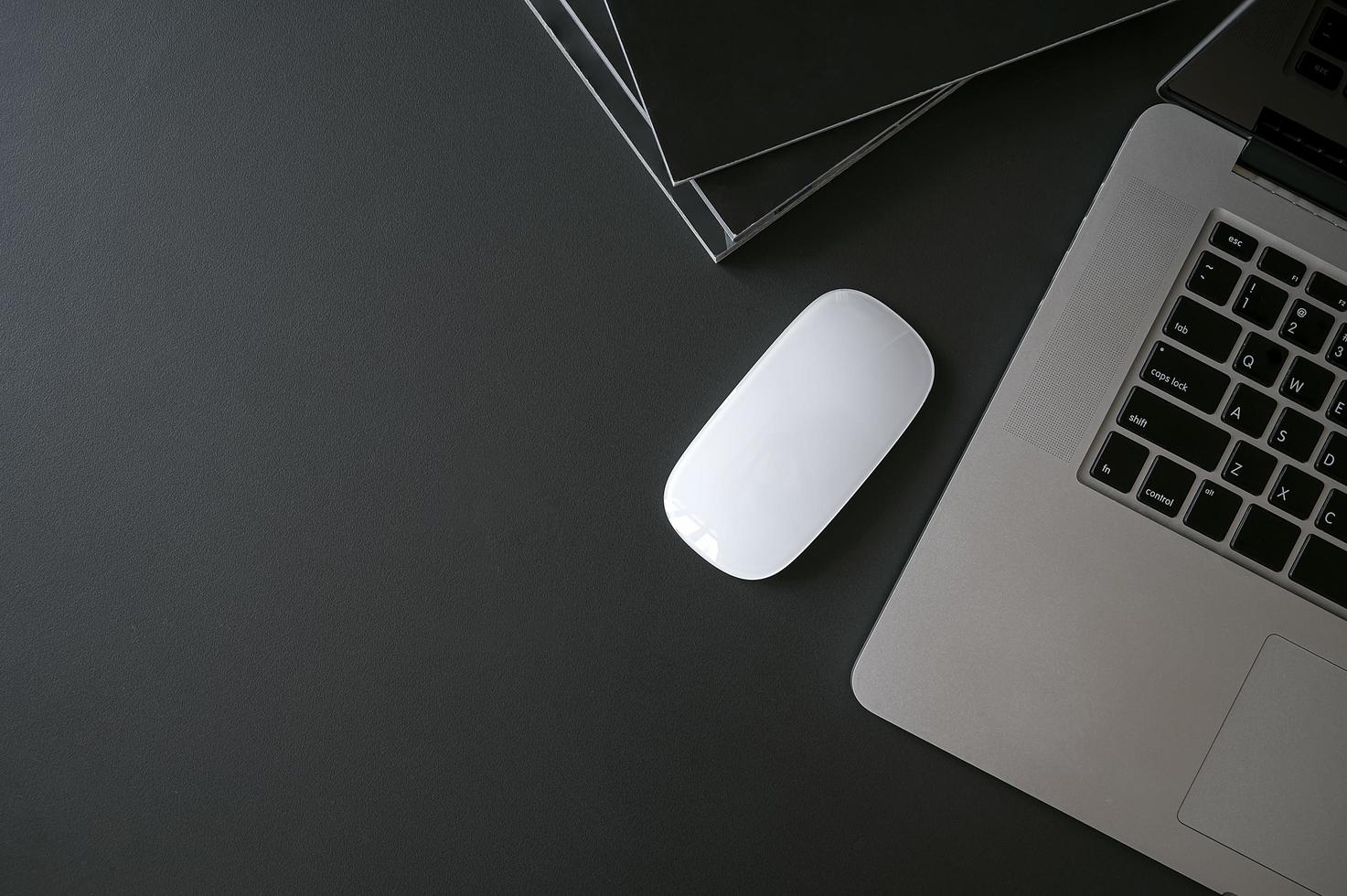 Laptop, mouse and books on a black table photo