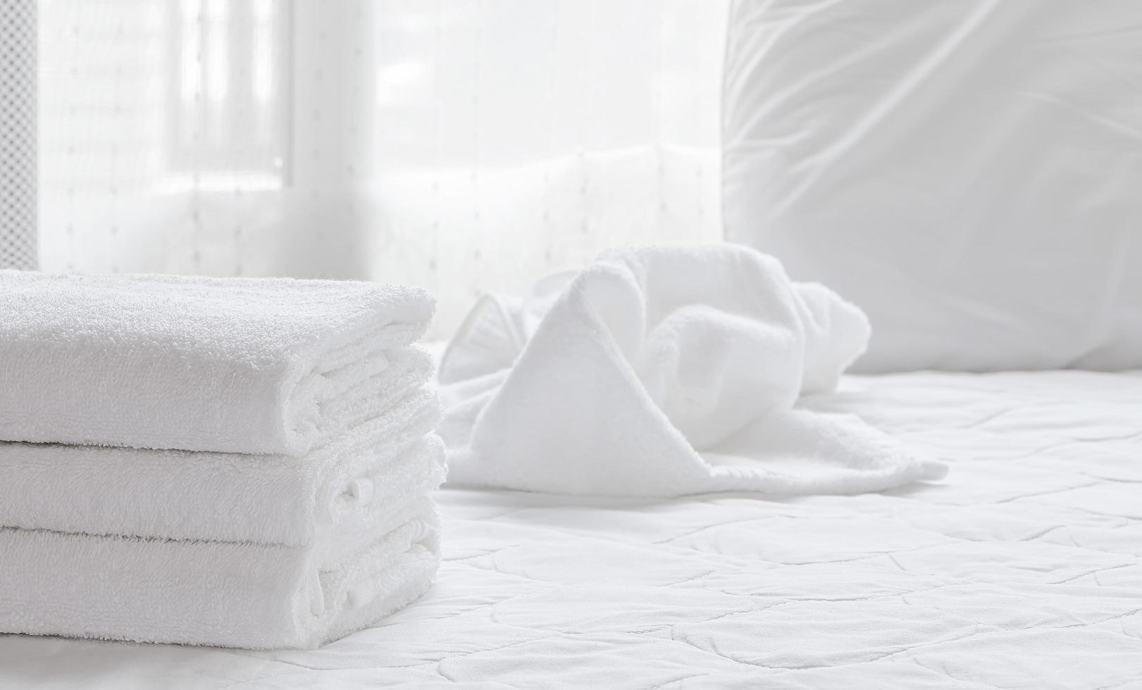 Folded clean towels on a white bed sheet photo