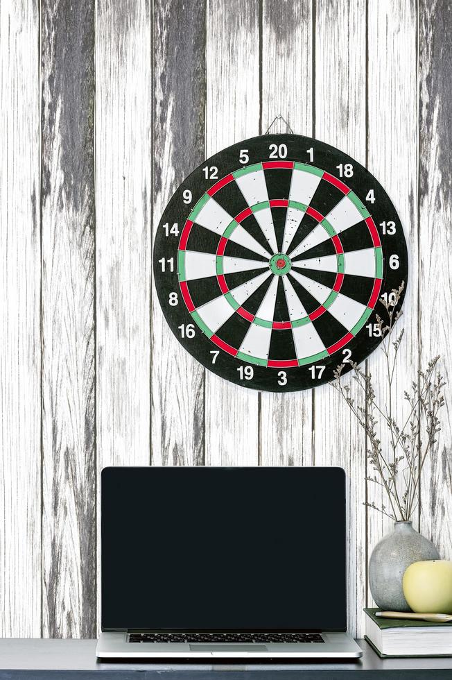 Laptop mockup with a dartboard on a wooden wall photo