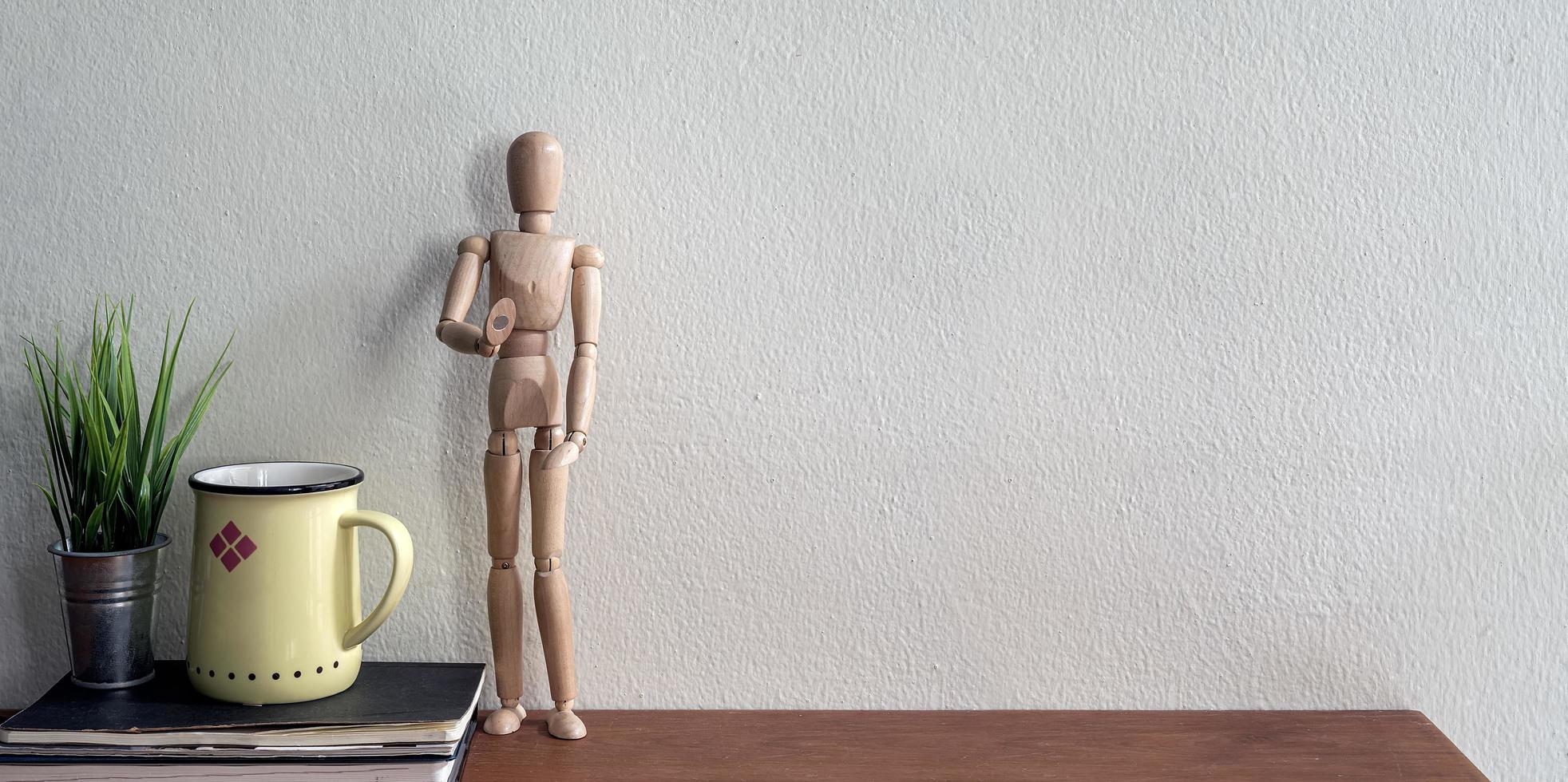 Wooden model with coffee cup and plant on a desk photo