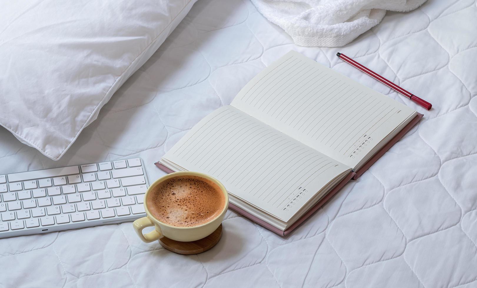 Coffee with a notebook and keyboard on a bed photo