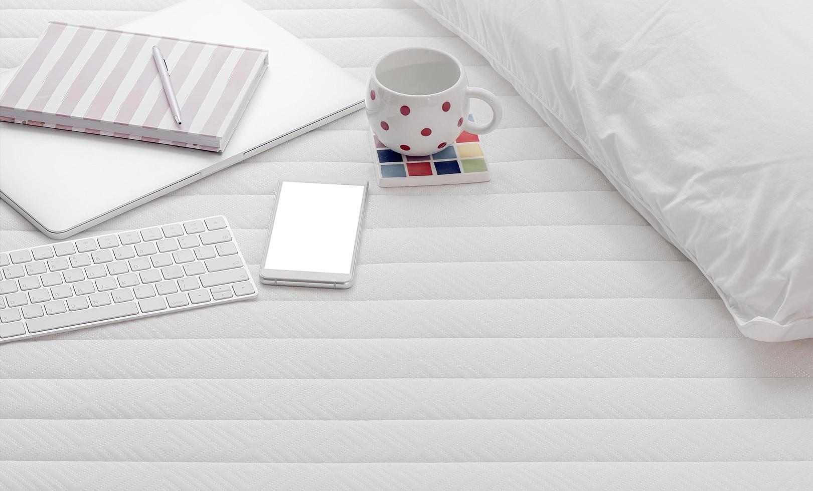 Smartphone mockup with a laptop and coffee on a bed photo
