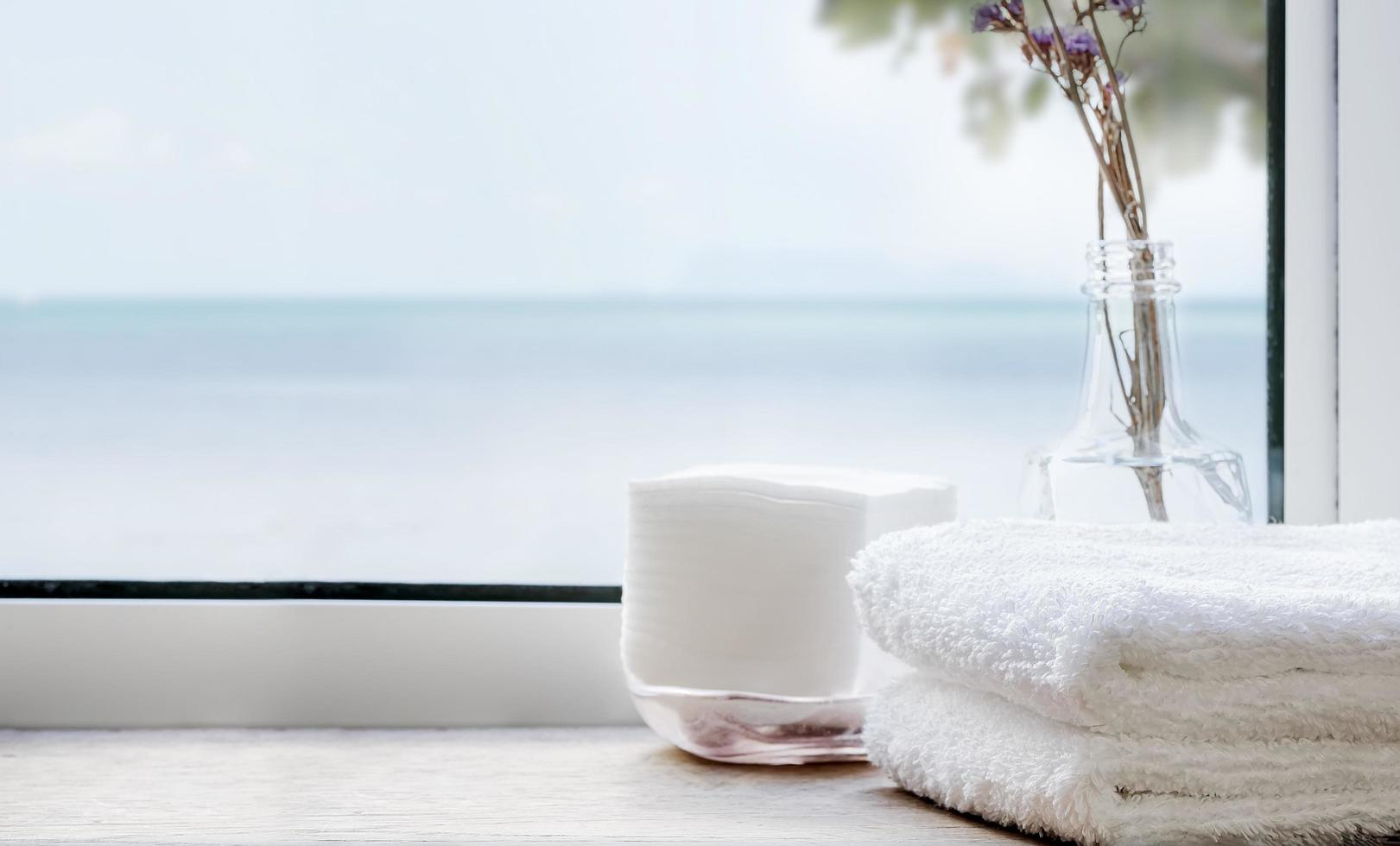 Stack of clean bath towels on a wooden table near a window photo