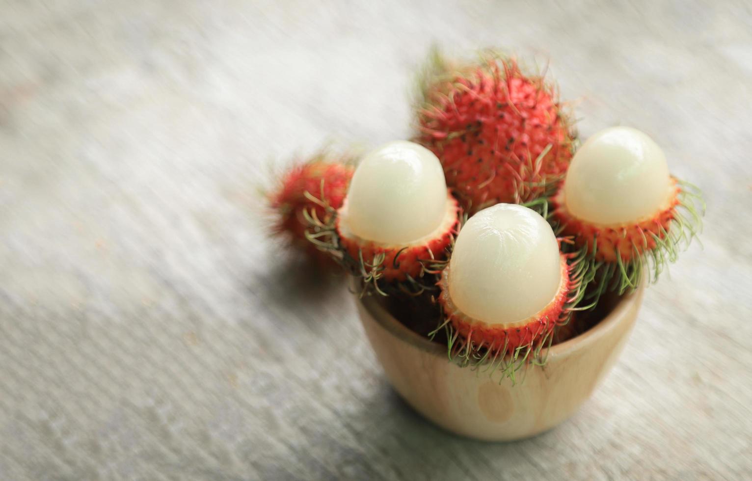 Peeling rambutan in wooden bowl photo