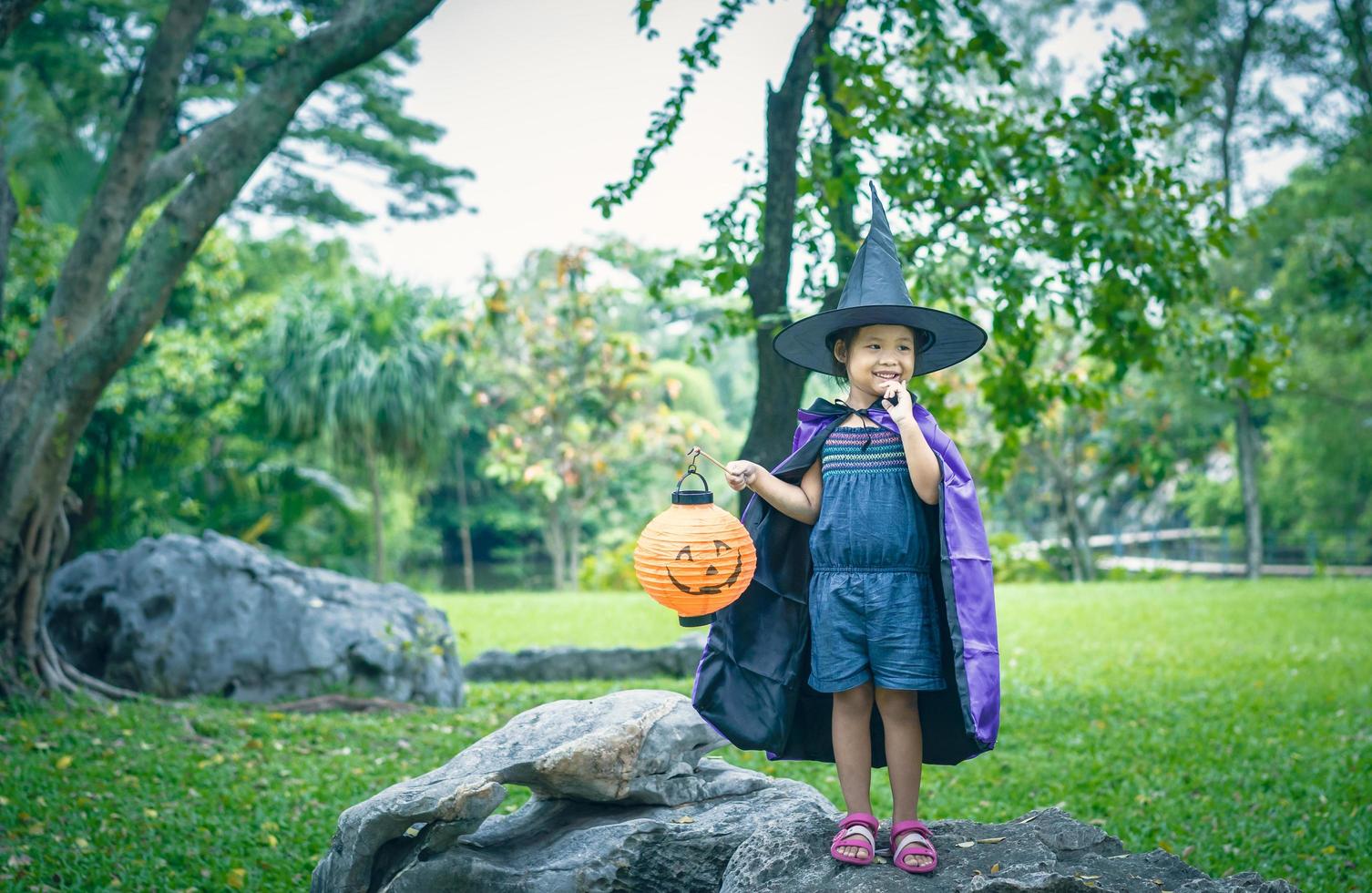 niña en un disfraz de bruja sosteniendo una lámpara de calabaza foto