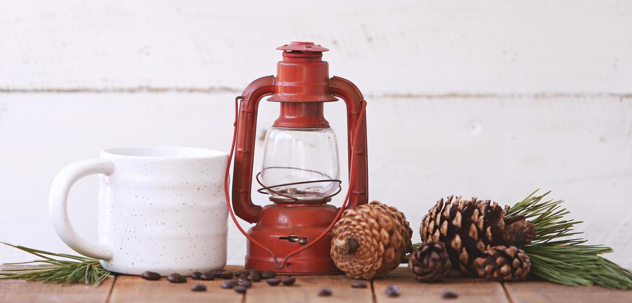 Lantern and a coffee cup with pinecones photo