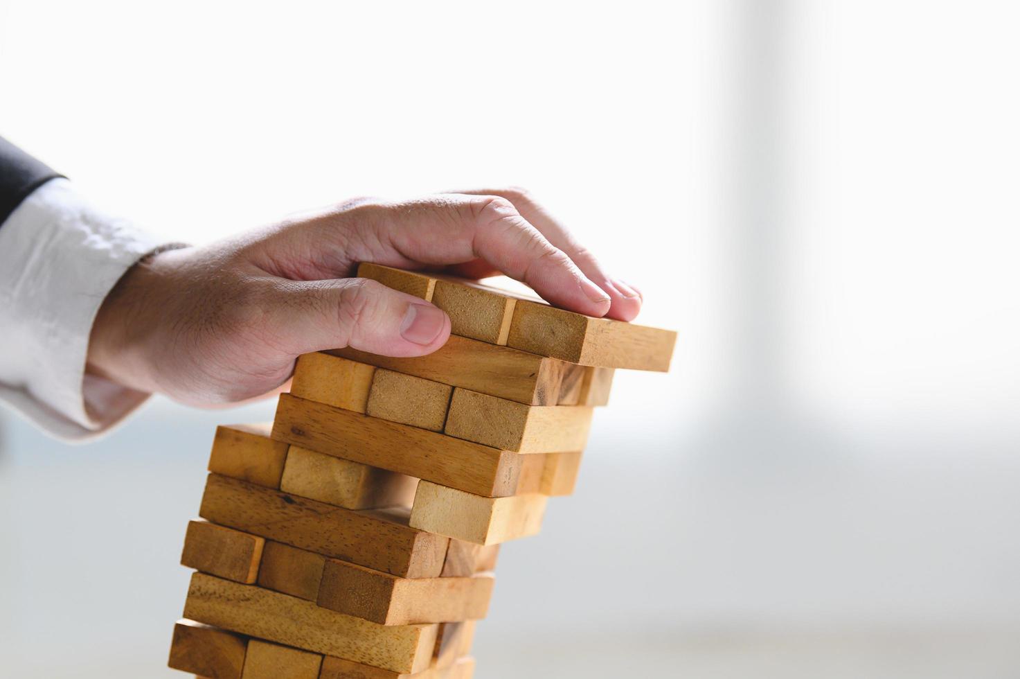 Businessman collapsing stacked wooden tower  photo