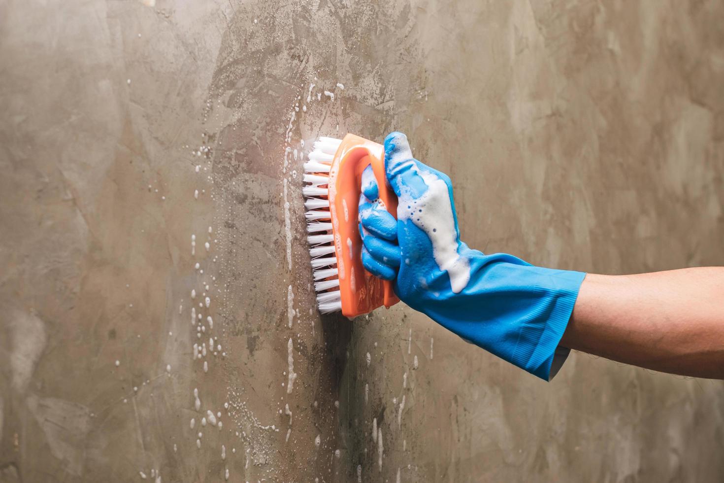 Close-up of a person cleaning a wall with a brush photo