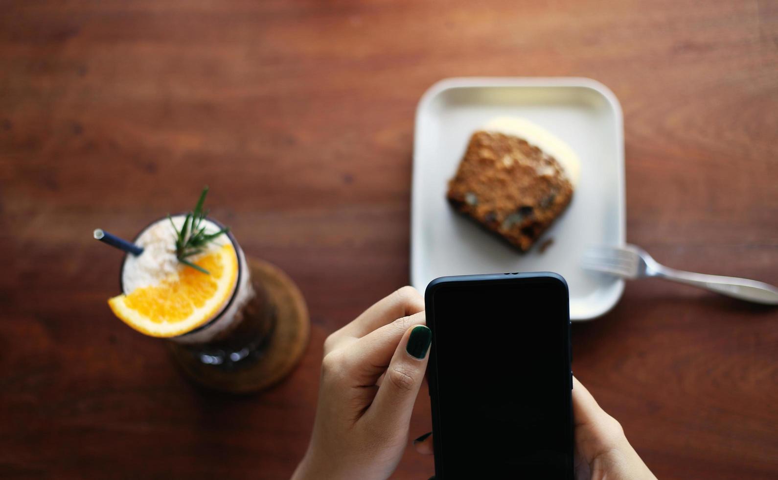 Girl uses mobile phone during coffee break in cafe photo