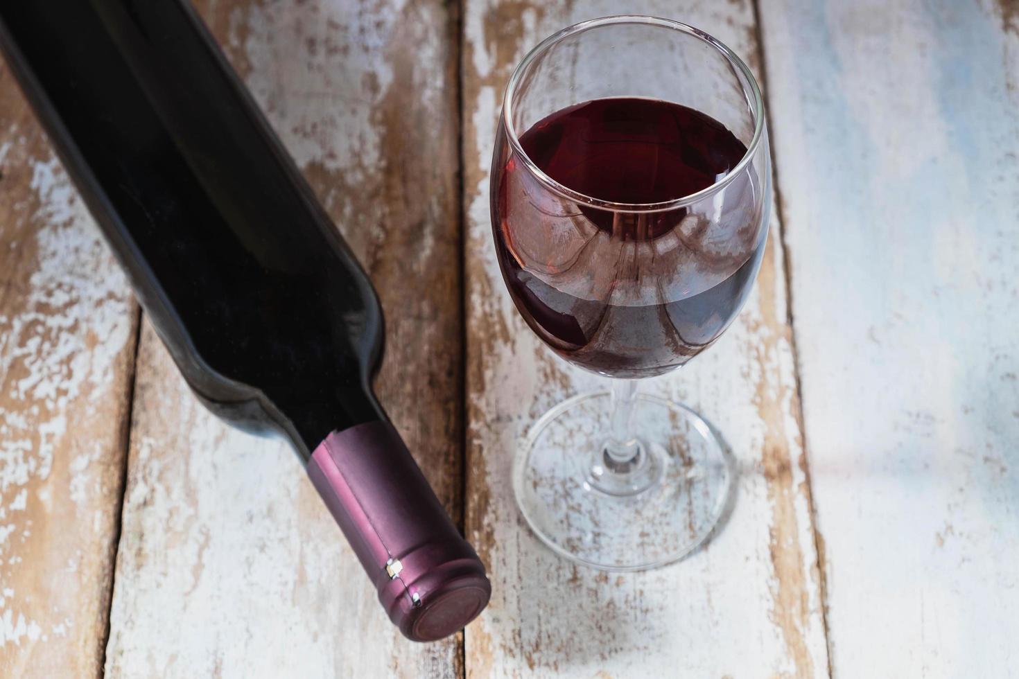 Copa de vino y botella de vino en la mesa de madera foto