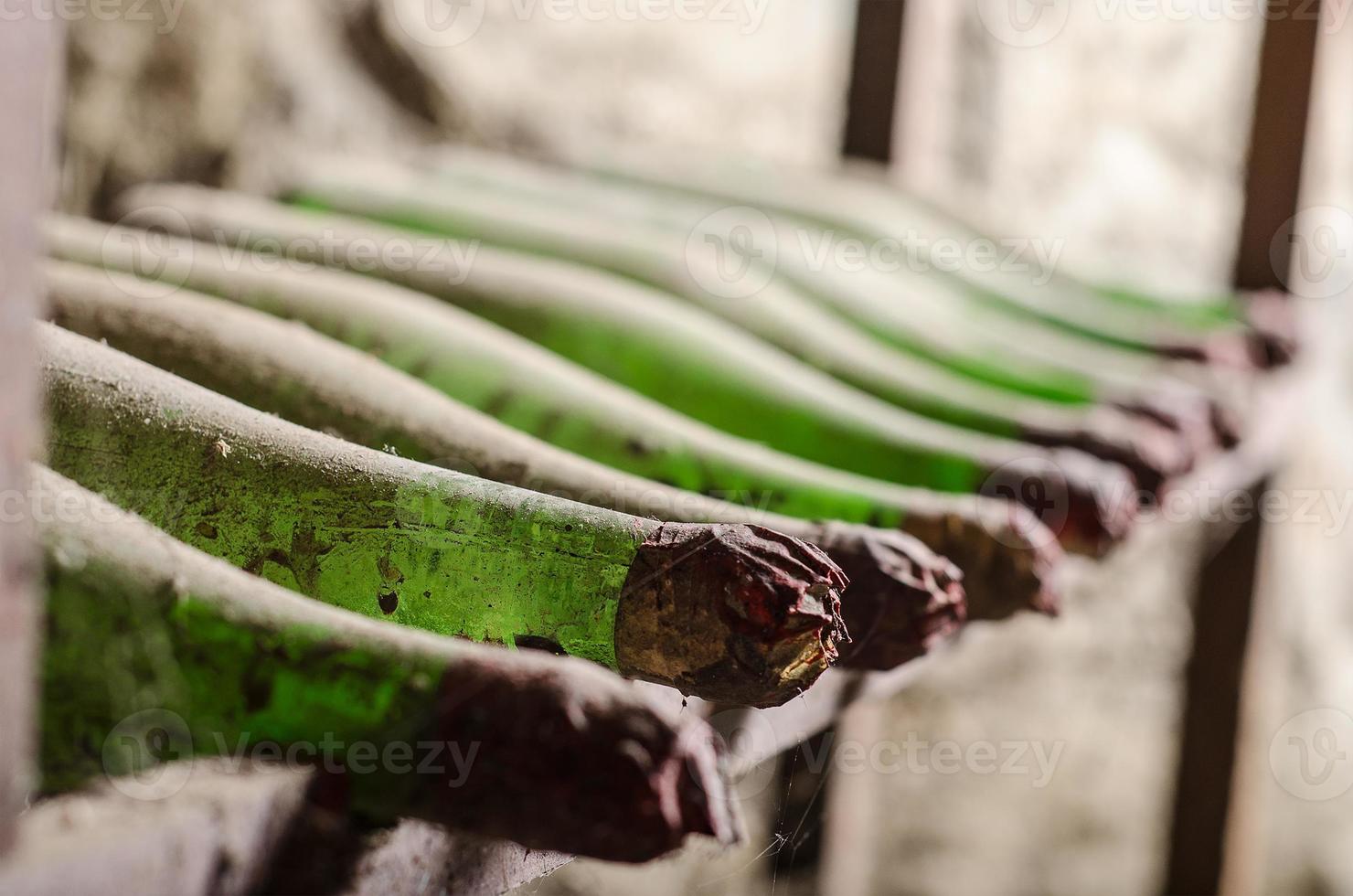 Viejas botellas de vino polvorientas en bodega foto