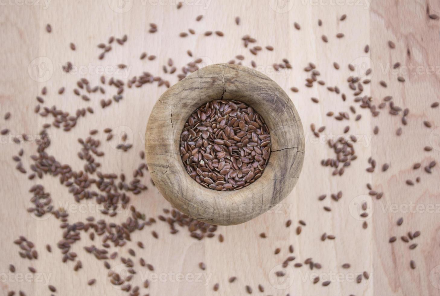 Flax seeds in olive wood bowl on wooden plate photo