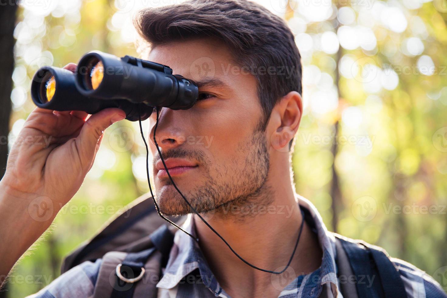 Man looking through binocular in the forest 1319150 Stock Photo at Vecteezy