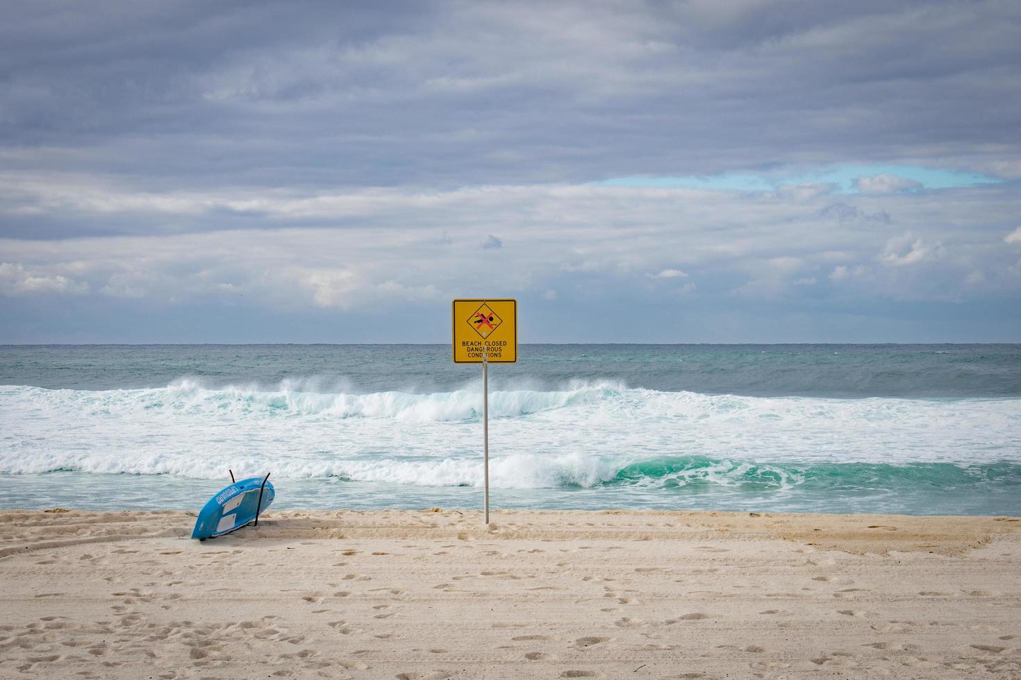 Blue surfboard at shoreline near signage photo