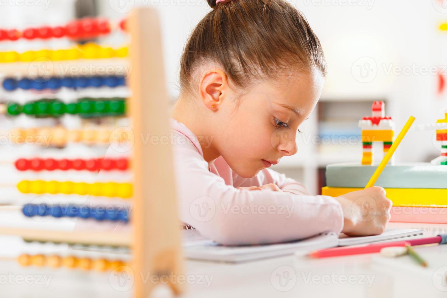 Little girl is doing homework at home photo