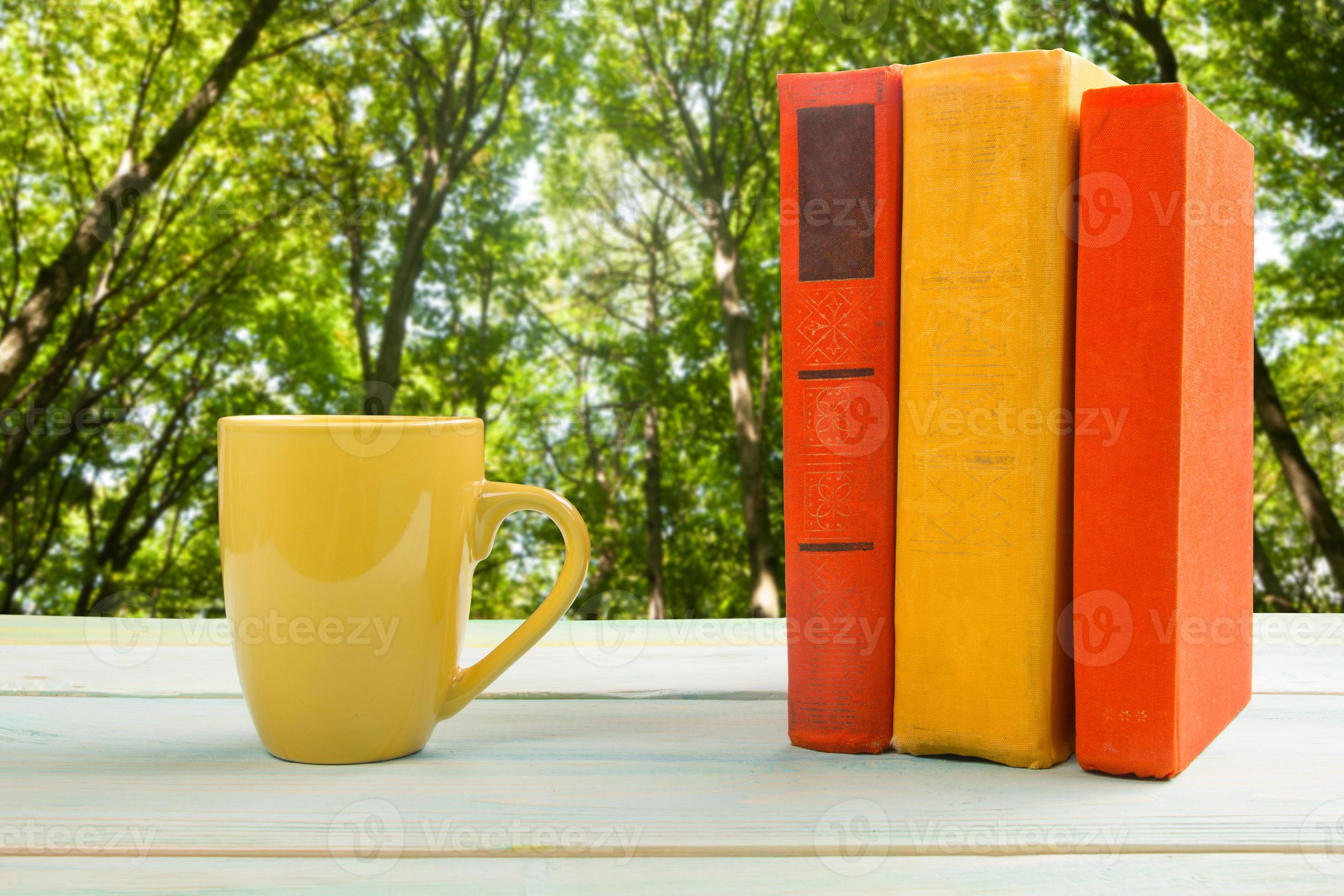 Stack of colorful books and cup on wooden table photo